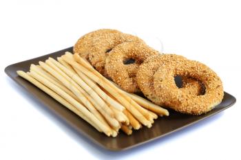 Round rusks and bread sticks on plate isolated on white background.