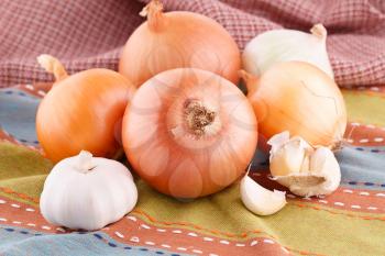 Onions and garlics on colorful towel.