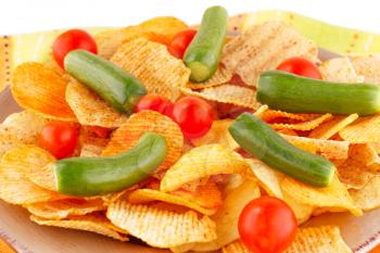 Potato chips and vegetables on plate.