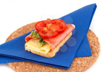 Sandwich on blue napkin on brown round board.