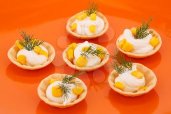 Cheese cream, sweet corn and dill in pastries in orange plate.