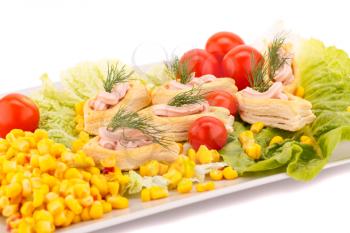 Fish cream in pastries, sweet corn, cherry tomato and lettuce on white plate.