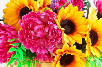 Colorful fabric flowers in wicker basket closeup picture.