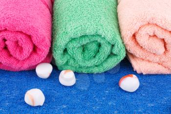 Colorful rolled towels with stones on plastic background.