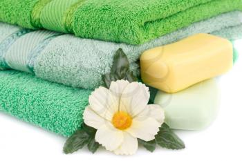 Folded towels, soaps and flower on white background.