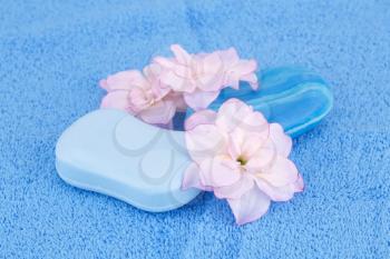Colorful soaps and flowers on blue towel.