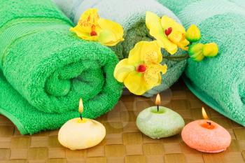 Spa set with towels, candles and flowers on bamboo background.