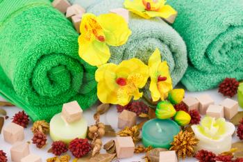 Spa set with towels, candles, wooden cubes and flowers closeup picture.