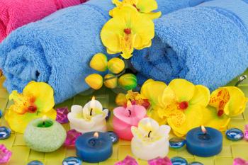 Spa set with towels, candles, stones and flowers on bamboo background.