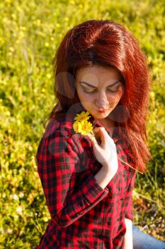 Young pretty woman with yellow daisy flowers in field.