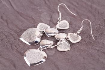 Silver earrings on fabric background.