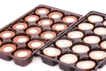 Assortment of chocolate in plastic boxes on white background.