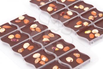 Chocolate with assortment nuts in plastic boxes on white background.