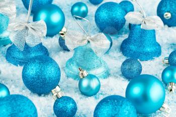Christmas decoration with blue balls and bells on the artificial snow background.