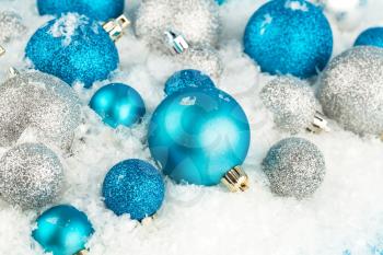 Christmas decoration with blue and gray balls on the artificial snow background.