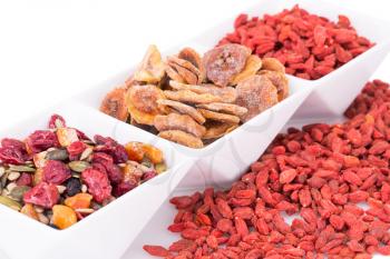 Dried fruits, berries and seeds in bowl on white background.