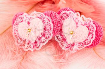 Two pink hearts with lace on feathers background.