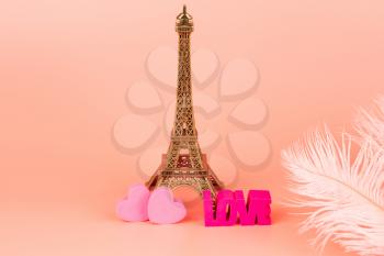 Valentine decoration with Eifel tower, pink hearts and feathers on pink background.