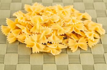 The heap of farfalle pasta on the green bamboo place mat.