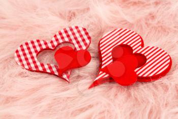 Two red hearts on pink fur background.