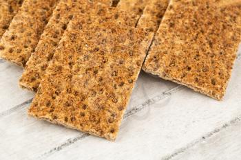 Pile of crackers with spices on gray wooden background.