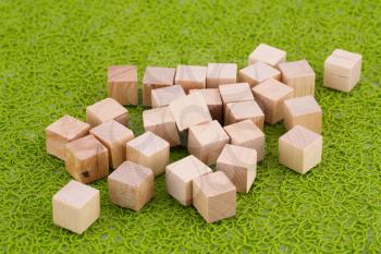 Wooden cubes on green plastic background.