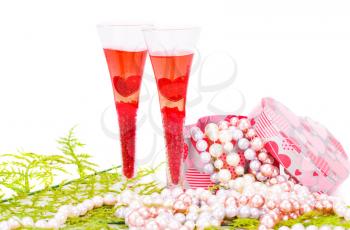 Two glasses, green leaves, colorful pearls necklaces and gift box on white background.