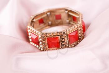 Ancient style bracelet with red stones on fabric background.