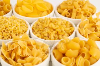Various kind of Italian pasta in the white ceramic bowls.