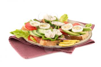 Sandwiches with sundried tomatoes, eggs, chicken, pepper, avocado and seeds, lettuce, lemon on beige  plate on towel on white background.