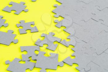 Unfinished jigsaw puzzle pieces on yellow background.