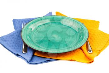 Green empty plate with knife and fork on blue and yellow  cotton towels.