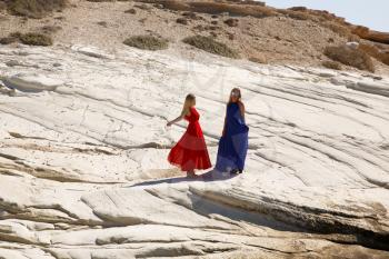 Blond women in the long dresses on the white rock in Cyprus.
