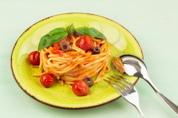 Pasta spaghetti Napoli or Napolitana on green plate on light green background. Italian cuisine.