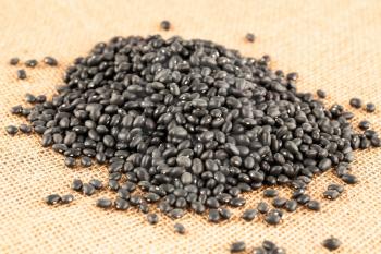 The heap of black turtle beans on burlap background.