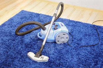 Powerful vacuum cleaner stand  on blue carpet.