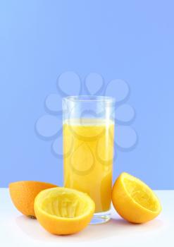 Glass of fresh orange juice with squeeze slice on blue background..