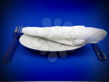 Table serving-knife,plate,fork and silk napkin  on  blue colour background.