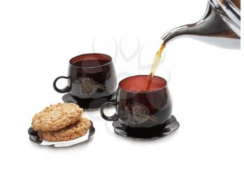 Still life - cookies, two cups and pouring tea. Isolated.
