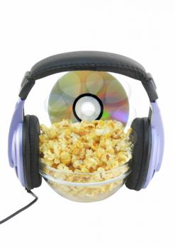 Bowl full of caramel popcorn with DVD disk and headphone . Isolated