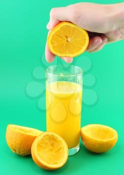 Glass of orange juice with hand, squeeze of orange.