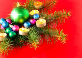 Christmas and New Year decoration-balls with fir branches and candels on red background .