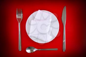 Table serving-knife,plate,fork and silk napkin  on  red colour background.