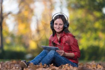 Young Girl With Headphones Enjoying Music In Autumn