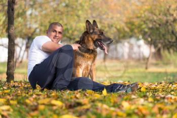 Adult Man Sitting Outdoors With His German Shepherd