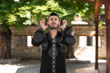 Young Muslim Man Making Traditional Prayer To God While Wearing A Traditional Cap Dishdasha