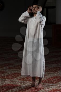 Young Muslim Man Making Traditional Prayer To God While Wearing A Traditional Cap Dishdasha