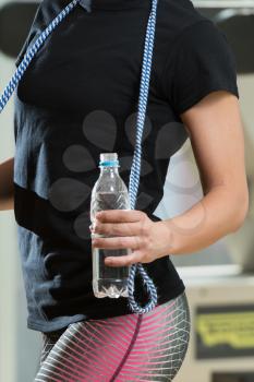 Fitness Woman With Jumping Rope - Holding A Bottle Of Water In Her Hand
