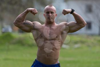 Bodybuilder Performing Front Double Biceps Poses In Park