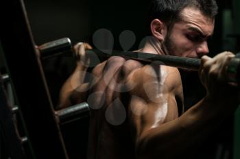 Young Man Performing Barbell Squats - One Of The Best Body Building Exercise For Legs